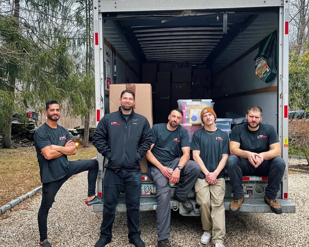 Pro Movers crew posing for a photo on a back of truck