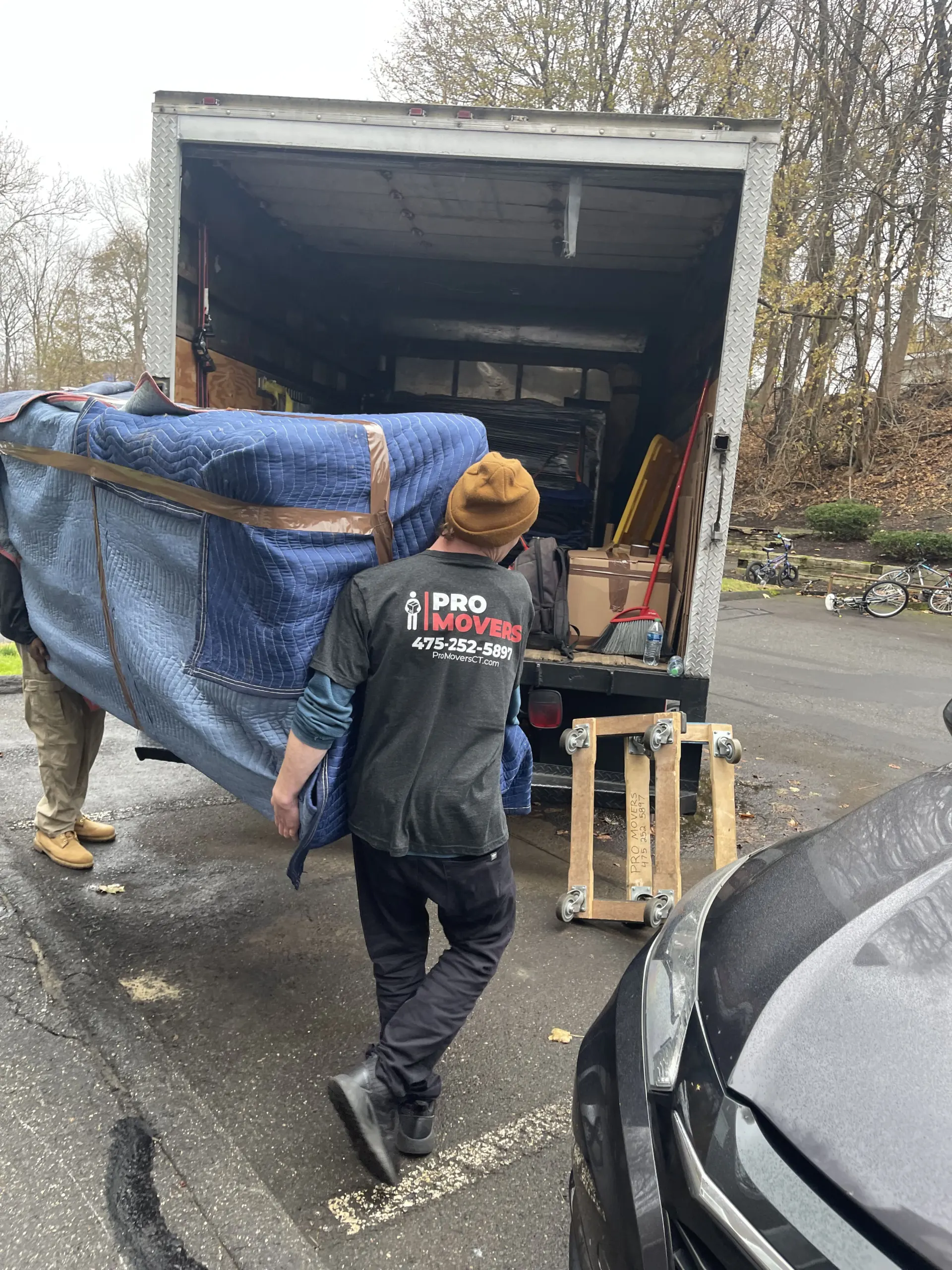 two members of Pro Movers loading a wrapped item in a moving truck