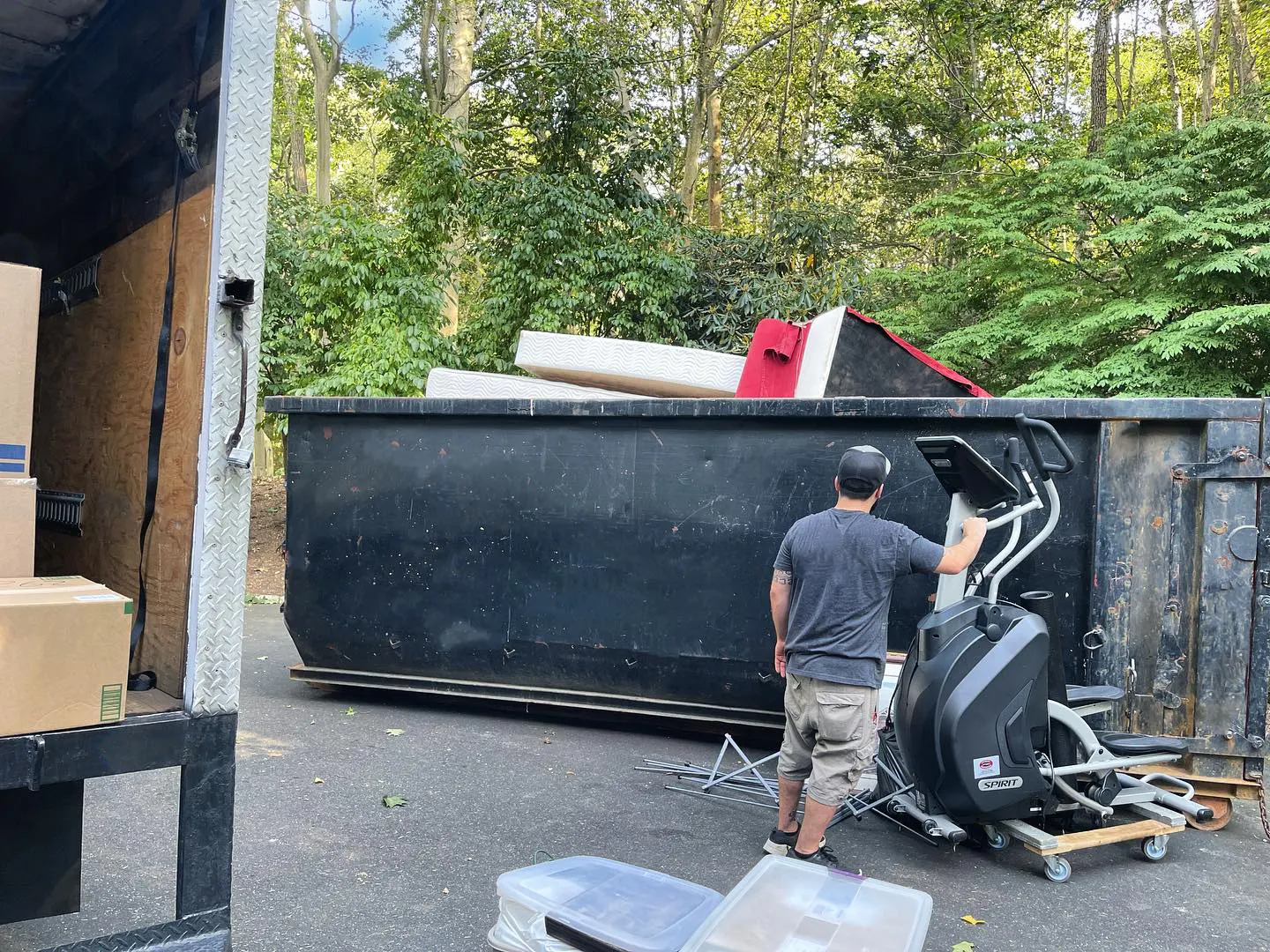 a member of Pro Movers in front of the container for junk removal with a gym machine
